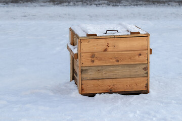 Wooden container with sand on a snowy street.