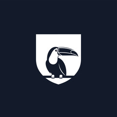 Obraz premium A minimalist graphic illustration of a black toucan bird perched on a branch inside a white shield emblem on a dark background.
