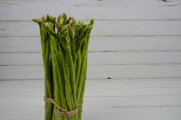 Bunch of fresh green asparagus stems on wooden background