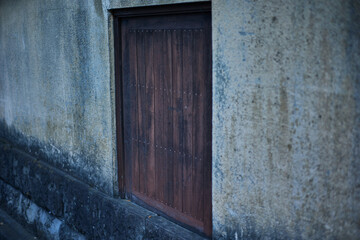 Traditional Japanese old mud wall texture with weathered wooden door background © NStock