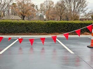Red flags hang over a freshly paved parking lot