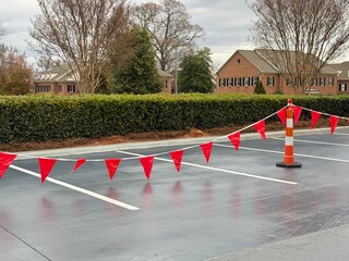 Red flags hang over a freshly paved parking lot
