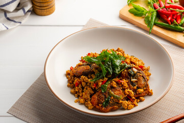 Stir Fried Crispy Basil with Pork and Black Preserved Egg in white plate (Kai Yiew Ma Kra Prao Krob)