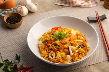 Stir fried instant noodle with Shrimp ,squid ,Cabbage and egg in white plate.instant noodle seafood