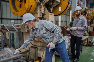 Industrial engineers wearing safety gear inspecting heavy machinery in a modern factory. Factory...
