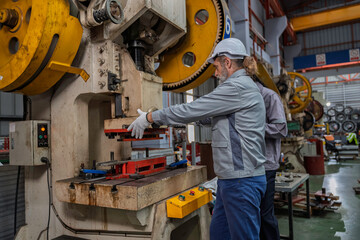 Industrial engineers wearing safety gear inspecting heavy machinery in a modern factory. Factory...