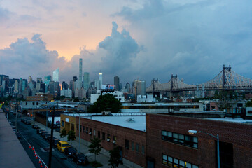 View of a vibrant cityscape where the buildings rise against the backdrop of a dramatic sky as the bridge stretches across, New York City, New York, United States.