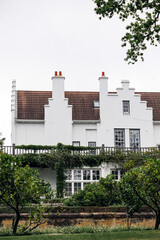 Large white estate house with a terracotta roof, surrounded by green foliage, creating a serene and...