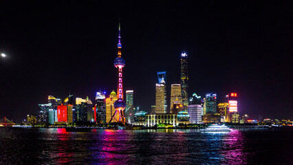 View of a vibrant Shanghai skyline ablaze with lights reflecting in the dark waters, dominated by the iconic Oriental Pearl Tower, Shanghai, Shanghai, China.