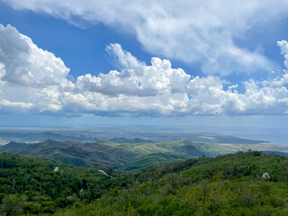 Lush green mountains landscape overlooking the southern Cuba coastline under dramatic clouds sky, elevated view