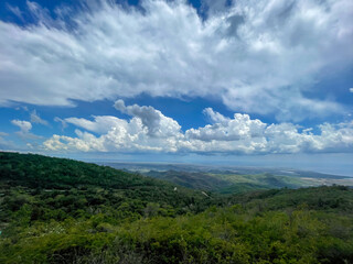 Obraz premium Lush green mountains landscape overlooking the southern Cuba coastline under dramatic clouds sky, elevated view