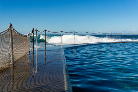 View of the ocean's raw power crashing against the pool barrier, its turquoise waters contrasting with the white spray, Bronte Baths, New South Wales, Australia.