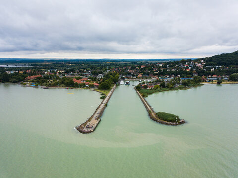 Aerial view of the Fony&oacute;di m&oacute;l&oacute; stretching out into the tranquil waters under a vast sky, its stone structure contrasting with the lush greenery, Fonyod, Hungary.