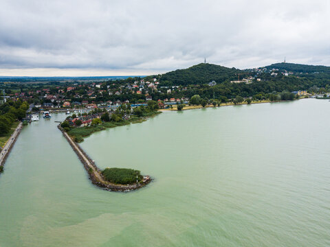 Aerial view of the Fony&oacute;di m&oacute;l&oacute; extending into the serene, green-tinted waters under a vast sky, Fonyod, Hungary.