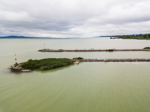 Aerial view of the tranquil Fony&oacute;di m&oacute;l&oacute; stretches into the calm, grey-green waters under an overcast sky, Fonyod, Hungary.