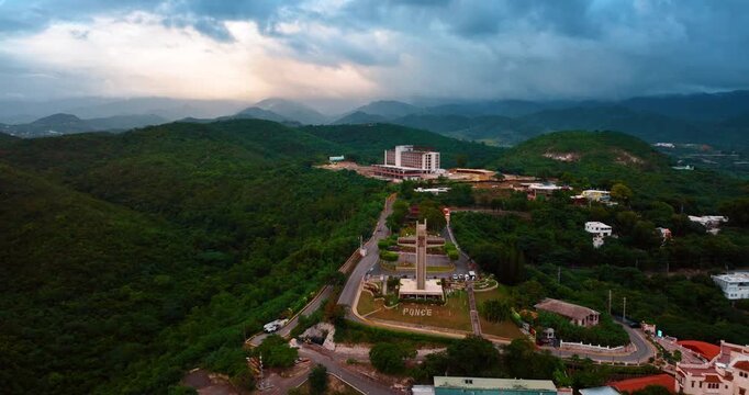 Approaching the Watchman Cross in the green scenery of Ponce, Puerto Rico. Dark dramatic cloudscape gathered in the sky over the mountains. Aerial view.