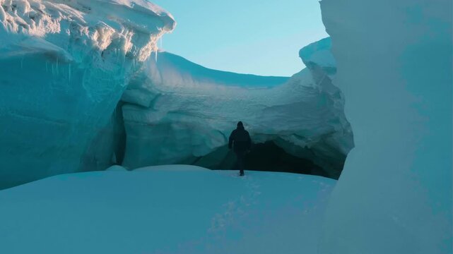 Walk inside incredible blue frozen cave unique grotto sharp icicles, lot of ice stalactites hang from ceiling. Best nature. Winter frozen glacier. Travel. Mysterious film