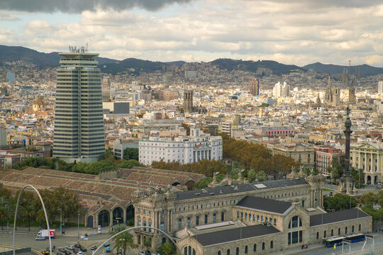 View of the cityscape unfolds with the Torre Mapfre skyscraper rising amidst the buildings, seen from above, with mountains in the distance, Barcelona, Catalonia, Spain.