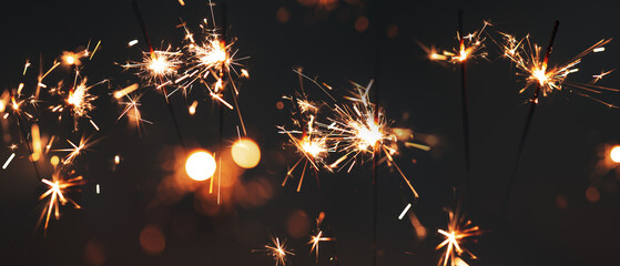 Burning sparklers in the night sky with glowing bokeh. Horizontal background for new year's and...