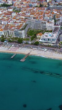 4K aerial vertical video of Cannes Croisette beach and JW Marriott Hotel. Cinematic drone footage of French Riviera luxury coastline and turquoise sea. Ideal for travel reels and mobile stories.