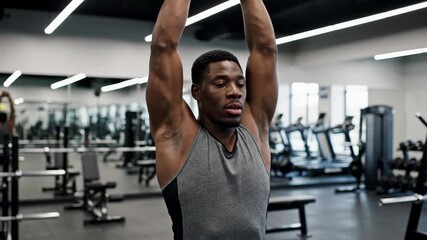 Fit man exercising in gym: arm lift reps in modern fitness center
