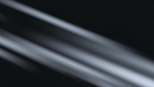 Blurry silver lines on a black background create a dynamic, abstract visual effect, evoking a sense of motion and modernity.