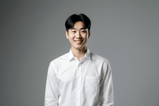 Smiling Korean male looking at camera isolated on gray background. Handsome young guy standing in studio, posing for picture