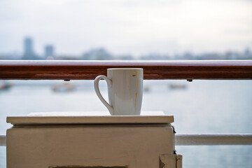 Morning coffee gone rogue  left dirty and lonely on the ship's metal box by the railing.
