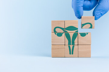 A doctor wearing a blue glove places wooden cubes with a uterus icon. Concept of cervical cancer...