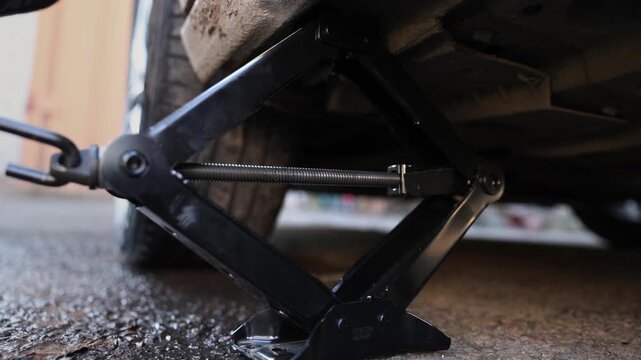 Jack screw lowers and raises car body before carrying out complex repair process. Special threaded tool shaped jack provides smooth movement of flat vehicle underbody and positioning