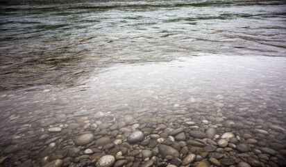 Rippling water over smooth stones in a serene riverbed at dawn
