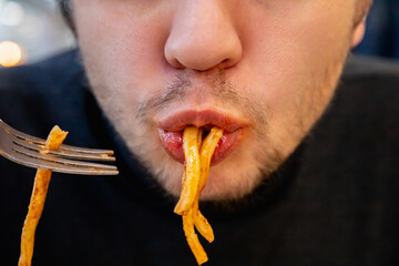 man eats fat pasta, sucks it with his mouth showcasing overeating and unhealthy eating habits....