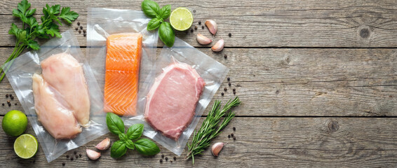 Vacuum-sealed bags with raw chicken, salmon, and veal on rustic wooden table with herbs