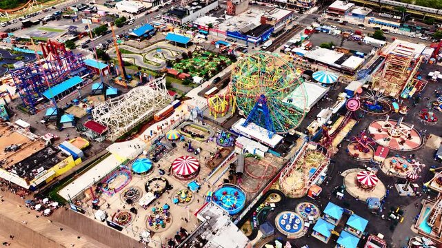 Aerial top view of brightly colored rides in Coney Island Luna Park. Swings, Ferris wheel, slides in an amusement park on the ocean shore.
