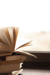 Old thick books on a dark windowsill near a large window