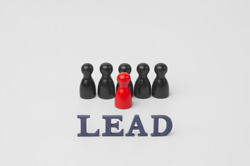 Red wooden leader figure guiding black team with LEAD text