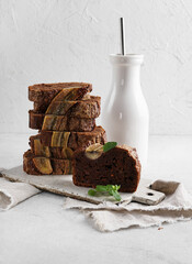 A Piece of chocolate banana bread with bottle of milk nearby. Stack of pieces of bread. Breakfast concept. Selective focus.