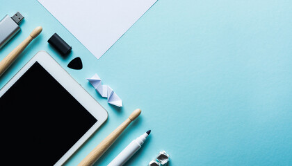 Office supplies and digital tablet on a blue background with stationery and storage devices