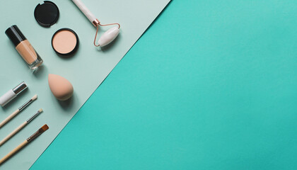 Assorted cosmetics and beauty tools arranged on a pastel teal background