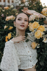 A young attractive Asian woman against a background of bush roses. A beautiful portrait of a woman in flowers.