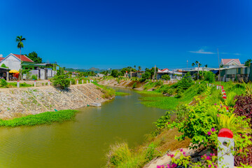 Obraz premium River channel (water channel).An artificial structure among rural buildings. Vietnam, the outskirts of Nha Trang city. 