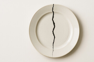 A white plate with a deep crack as a symbol of a break. Space for text.