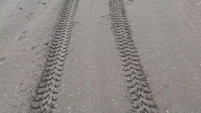 Point of view shot tracking the tire imprints of a vehicle along a rugged and remote stretch of sandy coastline. Capturing the essence of off road adventure in a pristine natural setting