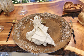 Close-up of Christmas table setting with ornate plate, folded napkin and white star decoration in festive atmosphere