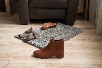 Brown leather ankle boot on floor near rug in home interior