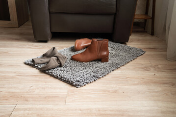 Pair of brown leather ankle boots on rug in cozy living room