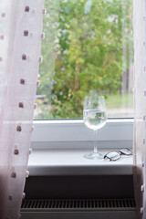 Wine glass and eyeglasses on windowsill in natural light