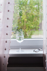 Empty wine glass on windowsill with soft daylight