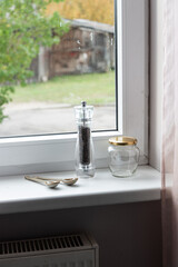 Empty spice jars and pepper mill on a windowsill
