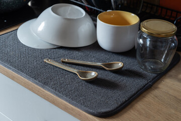 Clean washed dishes arranged on a gray drying mat on a kitchen countertop